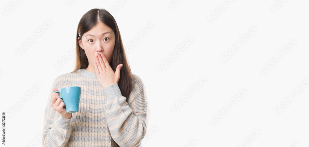 Young Chinese woman over isolated background driking cup of coffee cover mouth with hand shocked with shame for mistake, expression of fear, scared in silence, secret concept Young Chinese woman over isolated background driking cup of coffee cover mouth with hand shocked with shame for mistake, expression of fear, scared in silence, secret concept