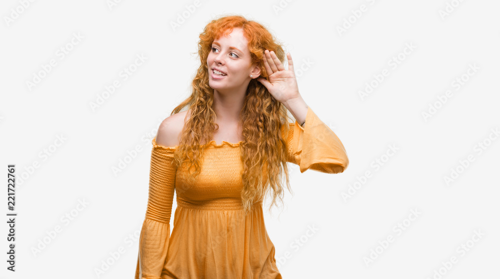 Young redhead woman smiling with hand over ear listening an hearing to rumor or gossip. Deafness concept. Young redhead woman smiling with hand over ear listening an hearing to rumor or gossip. Deafness concept.