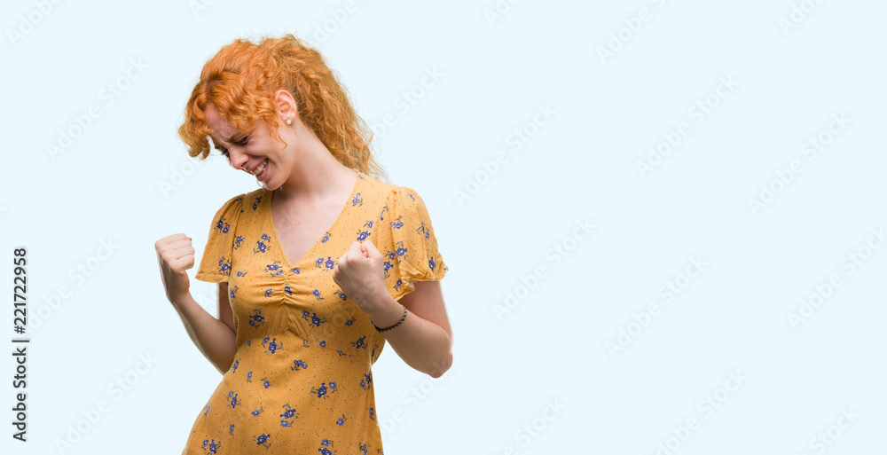 Young redhead woman very happy and excited doing winner gesture with arms raised, smiling and screaming for success. Celebration concept. Young redhead woman very happy and excited doing winner gesture with arms raised, smiling and screaming for success. Celebration concept.