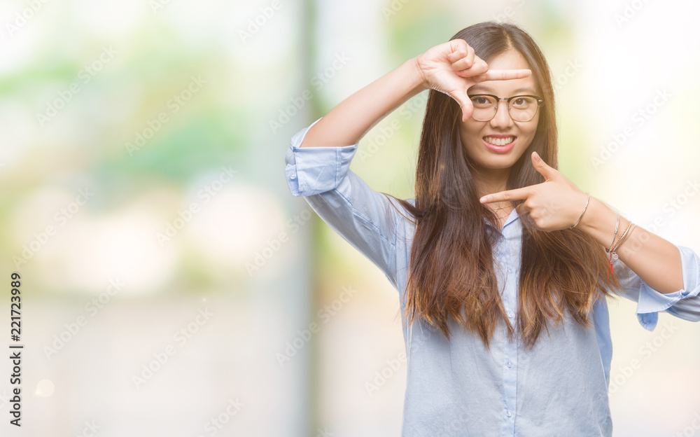 Young asian business woman wearing glasses over isolated background smiling making frame with hands and fingers with happy face. Creativity and photography concept. Young asian business woman wearing glasses over isolated background smiling making frame with hands and fingers with happy face. Creativity and photography concept.