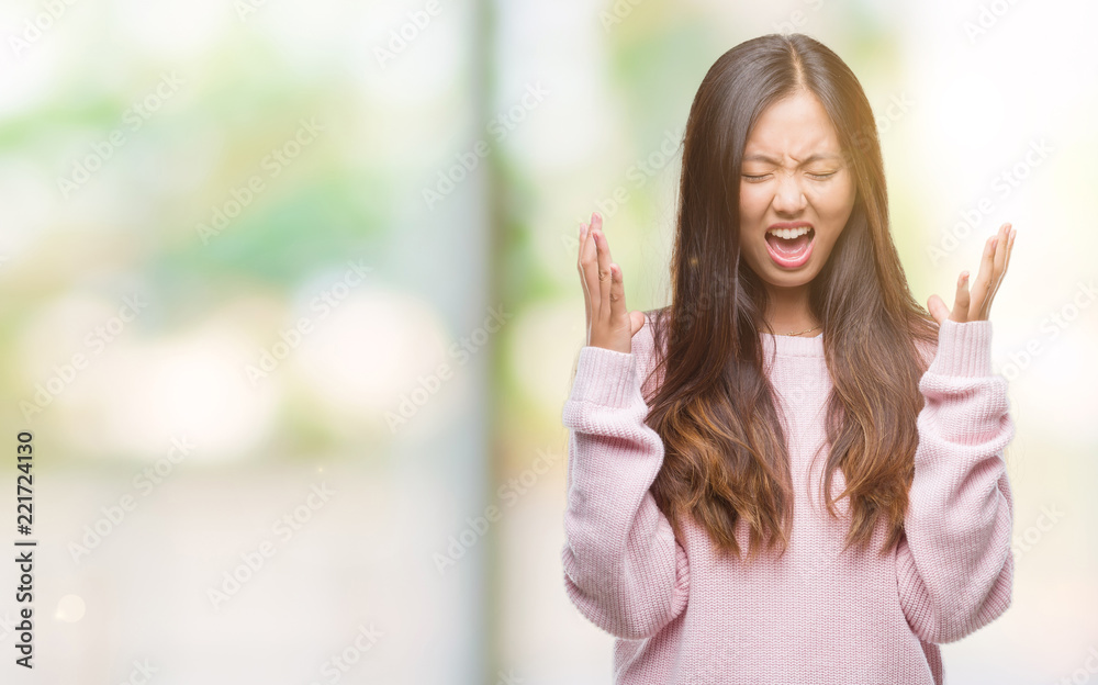 Young asian woman over isolated background celebrating mad and crazy for success with arms raised and closed eyes screaming excited. Winner concept Young asian woman over isolated background celebrating mad and crazy for success with arms raised and closed eyes screaming excited. Winner concept