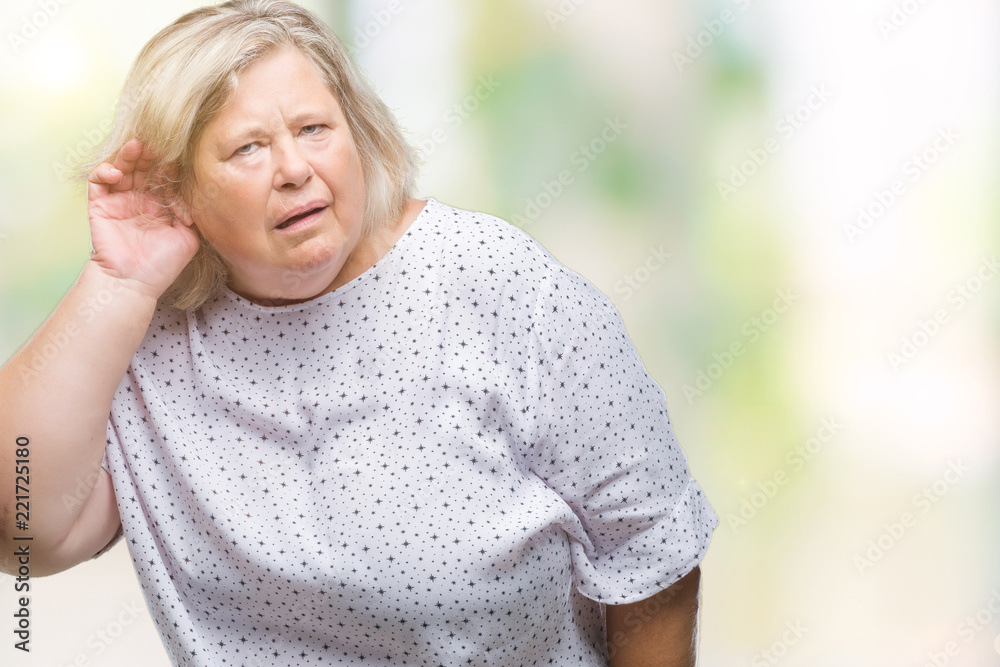 Senior plus size caucasian woman over isolated background smiling with hand over ear listening an hearing to rumor or gossip. Deafness concept. Senior plus size caucasian woman over isolated background smiling with hand over ear listening an hearing to rumor or gossip. Deafness concept.
