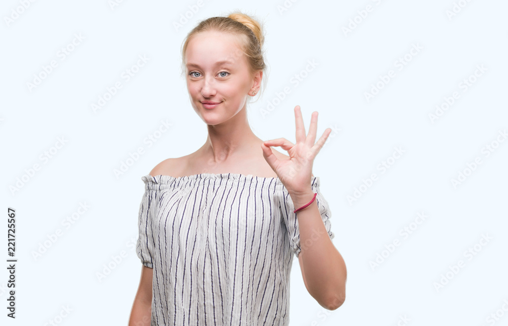 Blonde teenager woman wearing a bun doing ok sign with fingers, excellent symbol Blonde teenager woman wearing a bun doing ok sign with fingers, excellent symbol
