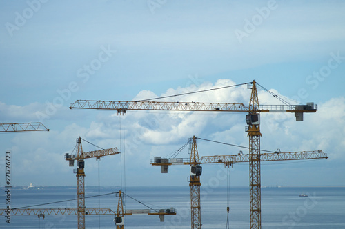 High construction cranes against the background of the sea and sky. Industrial landscape