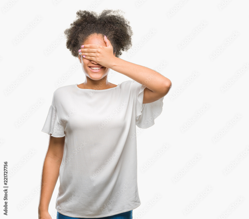 Young afro american woman over isolated background smiling and laughing with hand on face covering eyes for surprise. Blind concept. Young afro american woman over isolated background smiling and laughing with hand on face covering eyes for surprise. Blind concept.