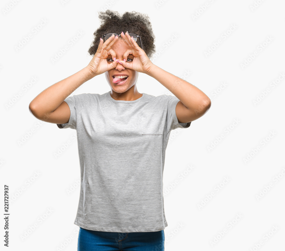 Young afro american woman wearing glasses over isolated background doing ok gesture like binoculars sticking tongue out, eyes looking through fingers. Crazy expression. Young afro american woman wearing glasses over isolated background doing ok gesture like binoculars sticking tongue out, eyes looking through fingers. Crazy expression.