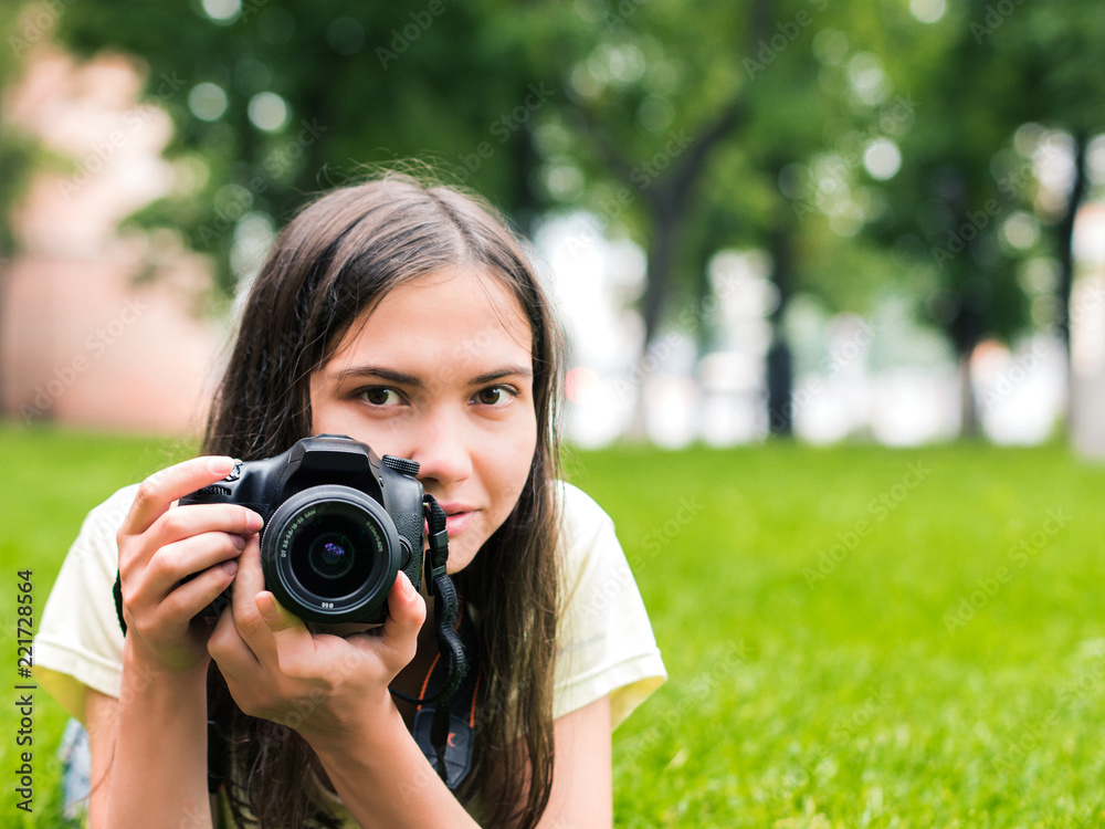 Young woman photographer with camera lie down on grass with copyspace. Focus at camera. Shallow DOF Young woman photographer with camera lie down on grass with copyspace. Focus at camera. Shallow DOF