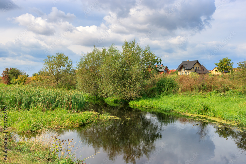 View of village pond against gray sky with clouds on a summer morning