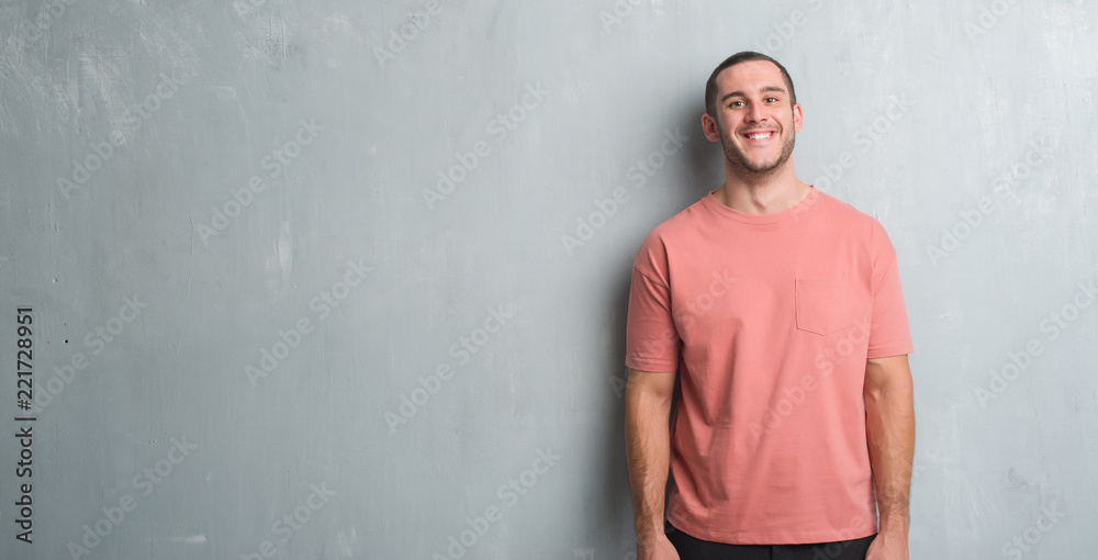 Young caucasian man over grey grunge wall with a happy and cool smile on face. Lucky person. Young caucasian man over grey grunge wall with a happy and cool smile on face. Lucky person.