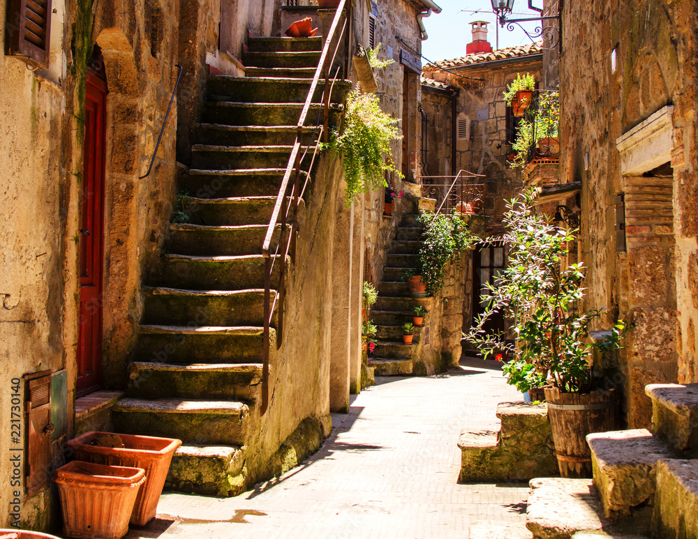 Naklejka premium Stary dziedziniec w Pitigliano z wazami z kwiatami i ze schodami.