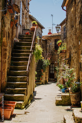 Old courtyard in Pitigliano with vases with flowers  and with stairs
