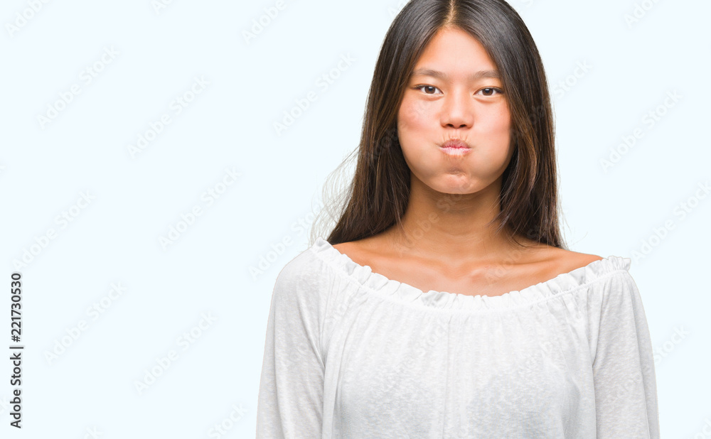 Young asian woman over isolated background puffing cheeks with funny face. Mouth inflated with air, crazy expression. Young asian woman over isolated background puffing cheeks with funny face. Mouth inflated with air, crazy expression.