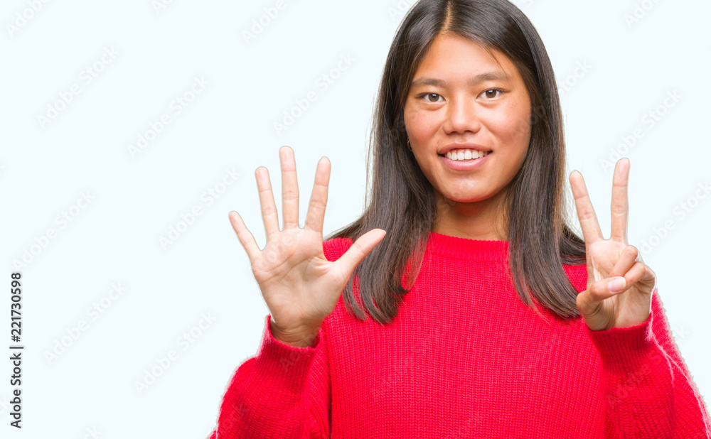 Young asian woman wearing winter sweater over isolated background showing and pointing up with fingers number seven while smiling confident and happy. Young asian woman wearing winter sweater over isolated background showing and pointing up with fingers number seven while smiling confident and happy.