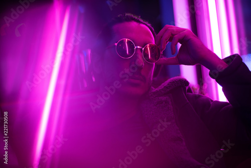 Long hair girl with sunglasses and leather jacket looking at neon lights