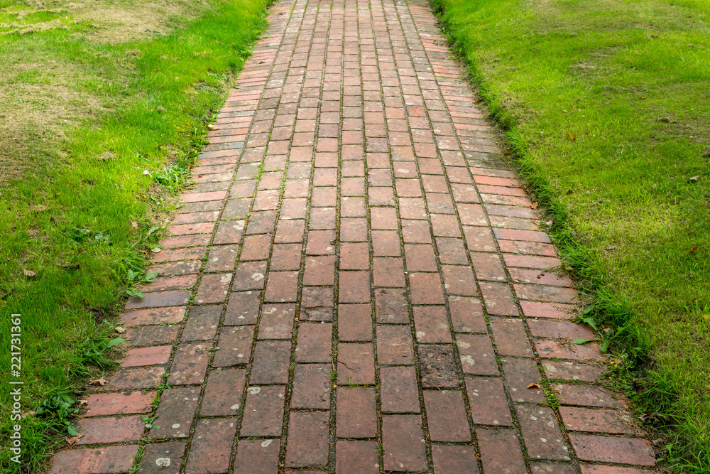 A red brick pathway in a Sussex Churchyard, with grass on either side