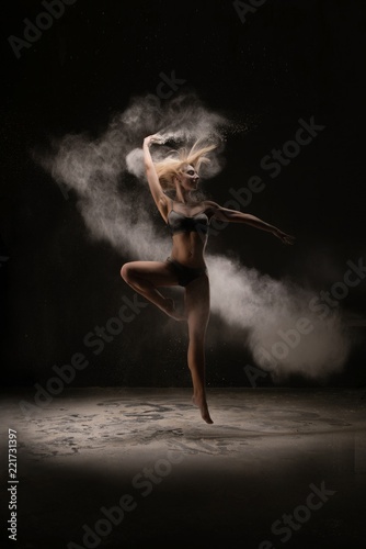 Fototapeta Naklejka Na Ścianę i Meble -  Slim woman dancing in white powder cloud