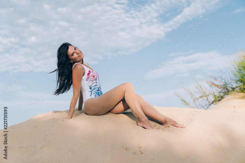 Attractive beautiful young girl having fun on the beach, posing lying on the sand, view from below, smiling broadly and having fun with her friends. The concept of beach vacation, tourism, travel Attractive beautiful young girl having fun on the beach, posing lying on the sand, view from below, smiling broadly and having fun with her friends. The concept of beach vacation, tourism, travel