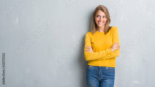 Beautiful young woman standing over grunge grey wall smiling looking side and staring away thinking.