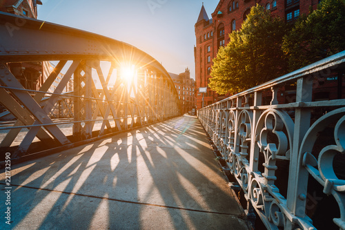 Metal arch bridge in the Speicherstadt of Hamburg with sunburst light during sunset golden hour