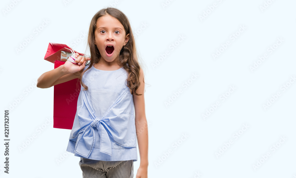 Brunette hispanic girl holding shopping bags scared in shock with a surprise face, afraid and excited with fear expression Brunette hispanic girl holding shopping bags scared in shock with a surprise face, afraid and excited with fear expression
