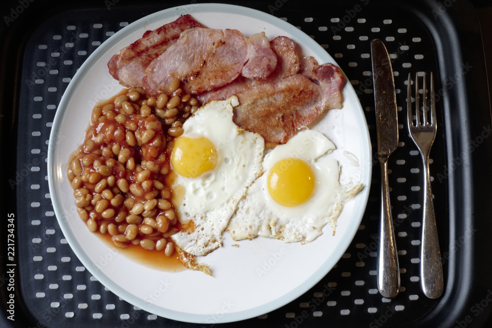 Fried breakfast view from above of bacon beans and eggs on plate and tray Fried breakfast view from above of bacon beans and eggs on plate and tray
