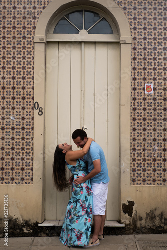 A happy laughing couple embracing in front of a door of an old mansion.