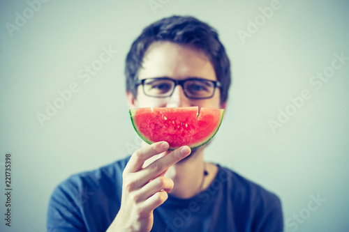 Junger Mann hält sich ein Stück Melone vor das Gesicht, Konzept