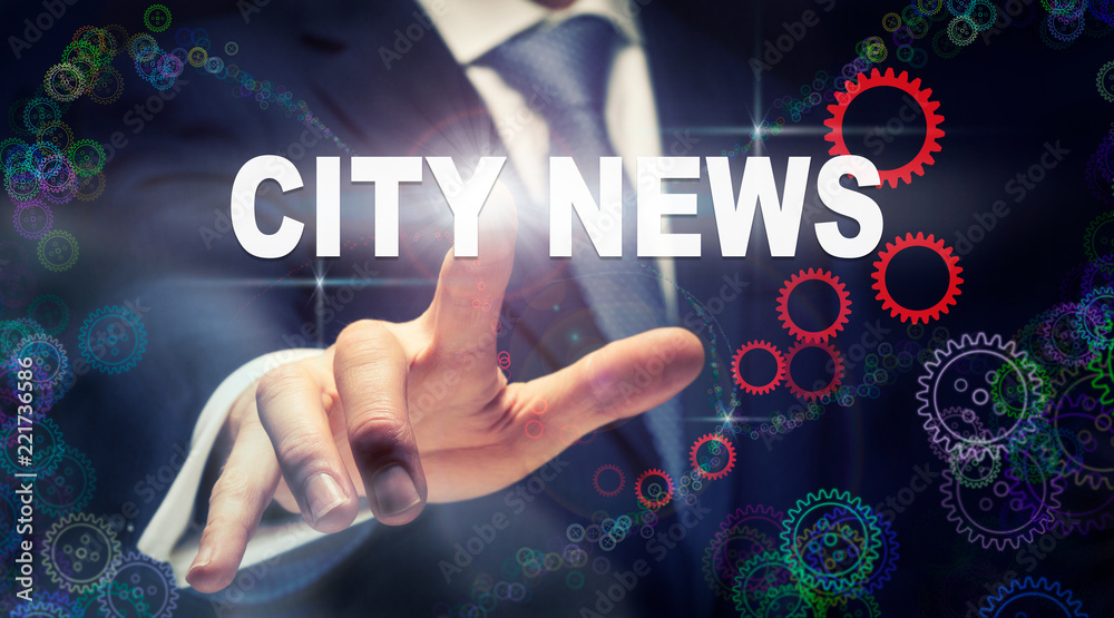 A businessman pressing a City News business concept on a graphical display of cogs A businessman pressing a City News business concept on a graphical display of cogs