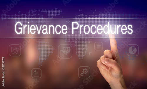 A hand selecting a Grievance Procedures business concept on a clear screen with a colorful blurred background.