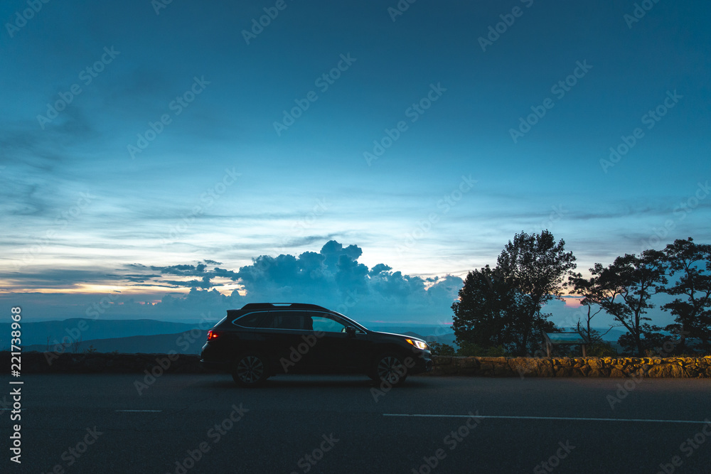 A black Subaru Outback is parked in front of an overlook in Shenandoah National Park, VA at sunset.