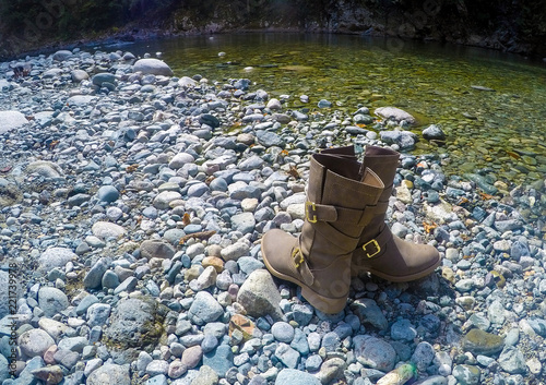 Cowboy Boots Beside A Riverbank on River Rock