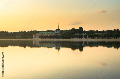 Summer sunset on the palace pond of museum-estate Kuskovo, Moscow. Russia. Mysterious moment when the orange sun says goodbye to nature. Its last reflection trembles on the water. 