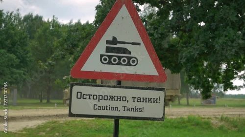 warning sign in the red triangle, against the passing military column. Translation. Caution, tanks! photo