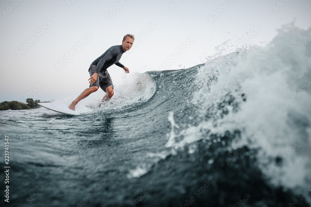 Man wakesurfing on the board down the blue water against the background of clear sky Man wakesurfing on the board down the blue water against the background of clear sky