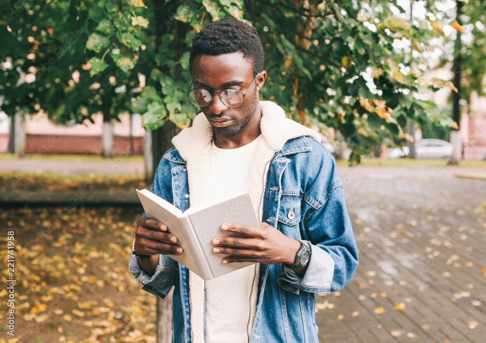 Obraz premium Fashion african man reading book in autumn city park