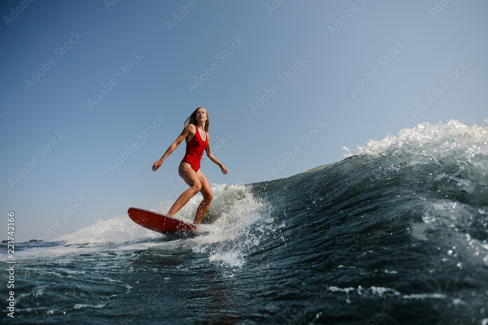 Beautiful slim woman wakesurfing on a high blue wave Beautiful slim woman wakesurfing on a high blue wave
