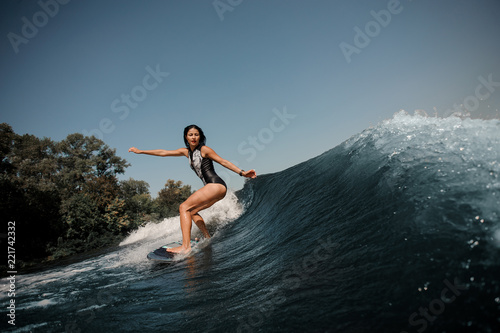 Sexy slim brunette woman wakesurfing on board down the blue water