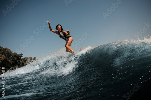 Active sexy brunette woman wakesurfing on board down the blue water