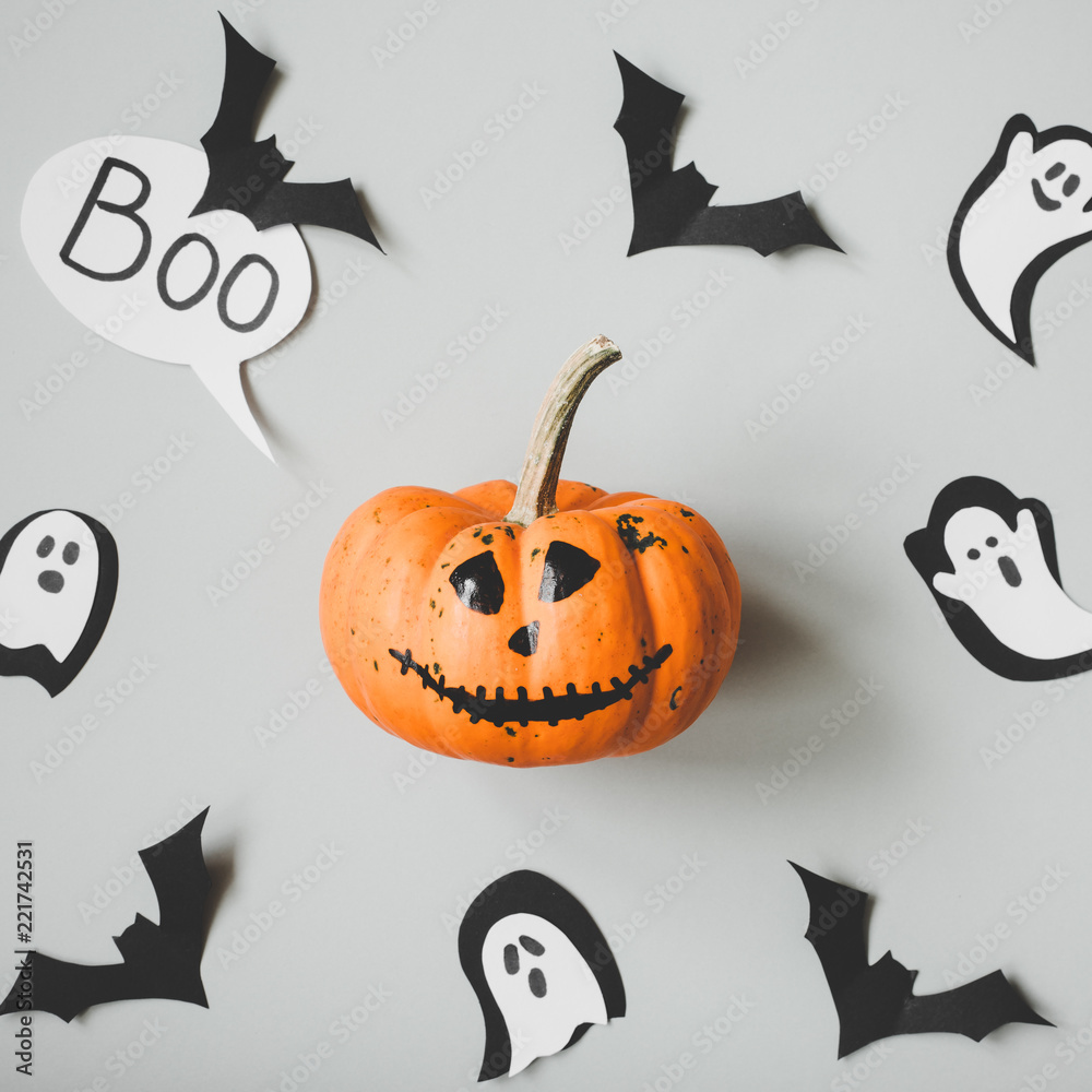 Fototapeta premium Happy halloween. Funny halloween pumpkin with paper bats and ghosts on gray background