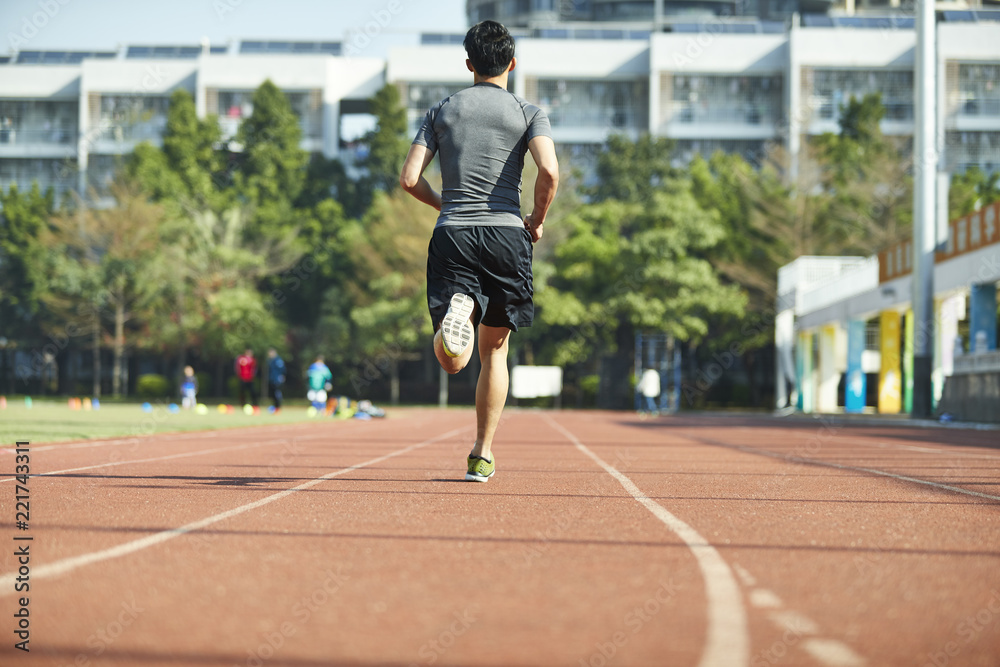 young asian male athlete running on track