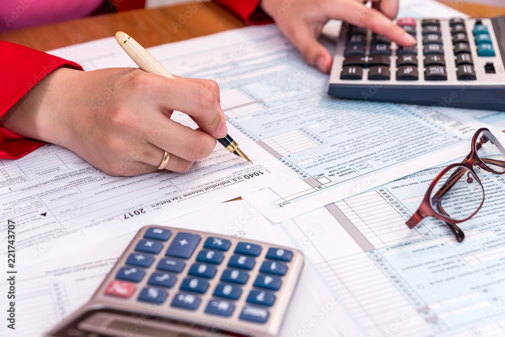 Female hand filling 1040 form and calculating Female hand filling 1040 form and calculating