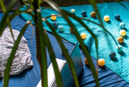 Grey Laptot Laying on Mattress with Turquoise Cover, Few Pillows and a White Background