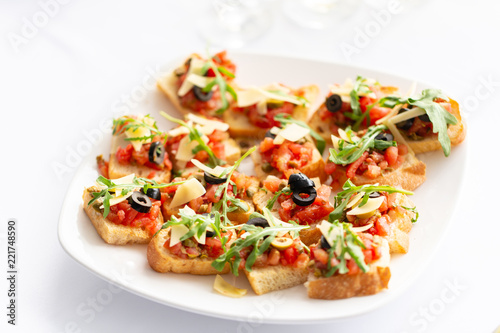 Plate with Italian appetizers. Bruschetta with a cherry tomatoes and shrimps. Parmesan cheese, olives, sun-dried tomatoes and walnuts.