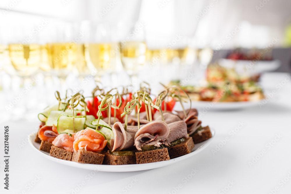 rye bread sandwiches, canapes, bruschetta on white plate. solemn banquet. Lot of glasses champagne or wine on the table in restaurant. buffet table with lots of delicious snacks.