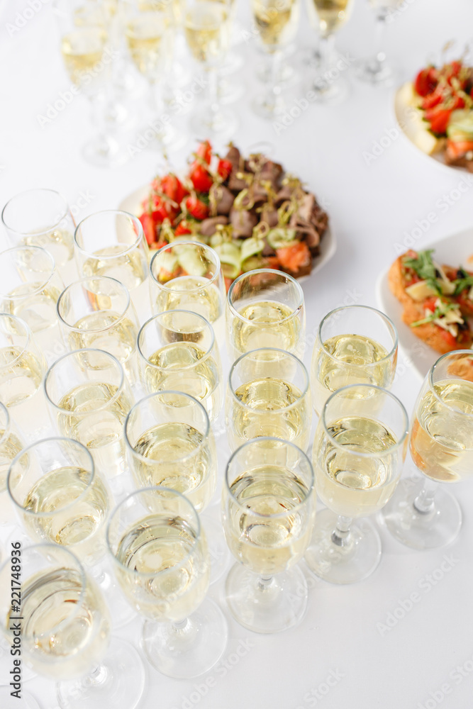 solemn happy new year banquet. Lot of glasses champagne or wine on the table in restaurant. buffet table with lots of delicious snacks. canapes, bruschetta, and little desserts on wooden plate board solemn happy new year banquet. Lot of glasses champagne or wine on the table in restaurant. buffet table with lots of delicious snacks. canapes, bruschetta, and little desserts on wooden plate board