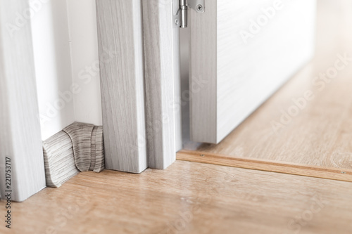 Room indoors. Hinge, jamb and plinth near doorway at the flat