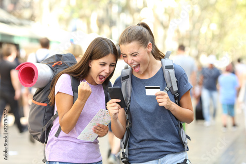 Excited backpackers buying online in the street photo