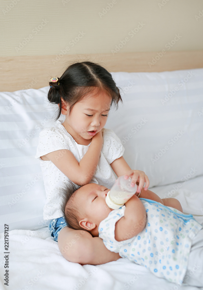 Young sister feeding little newborn brother by milk bottle on bed Stock  Photo - Alamy
