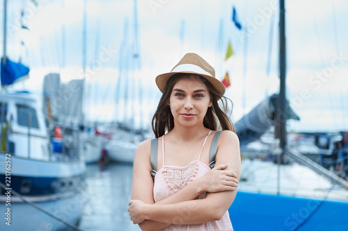 beautiful young woman travel girl on the background of a sea pier with boats and yachts, travel concept © evafesenuk