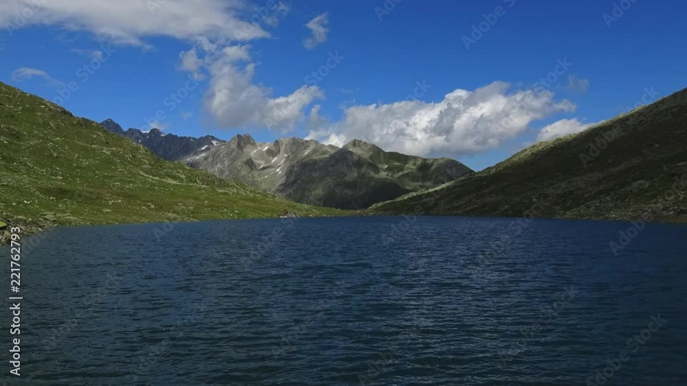 Time lapse view on peak of mountains and lake in Swiss Alps. Summer landscape, sunshine weather, blue sky and sunny day Time lapse view on peak of mountains and lake in Swiss Alps. Summer landscape, sunshine weather, blue sky and sunny day